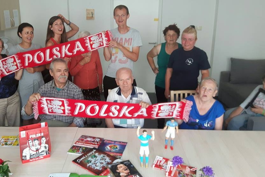 Uczestnicy wraz z terapeutkami trzymający szaliki z napisem Polska