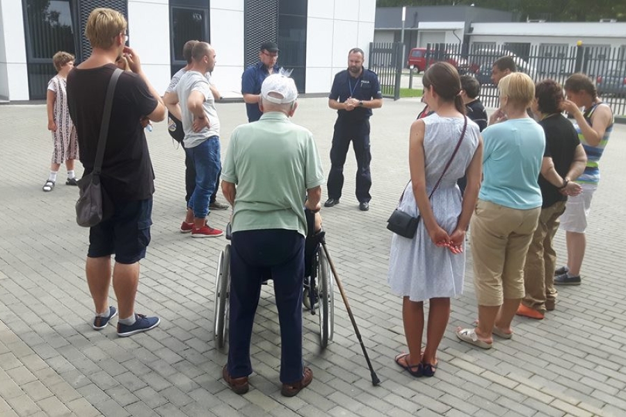 Uczestnicy stojący w kręgu, słuchający przemówienia funkcjonariusza policji