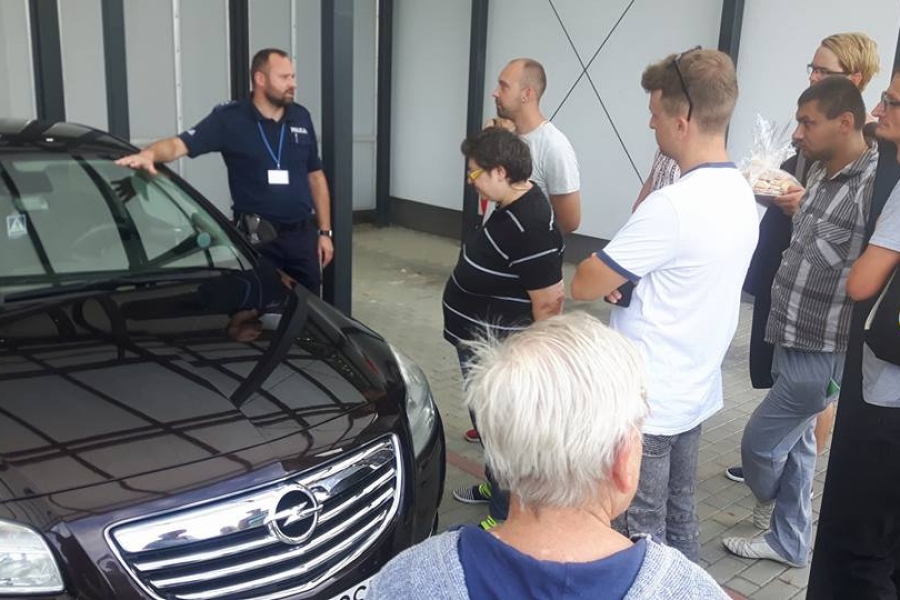 Policjant prezentujący uczestnikom służbowy samochód 
