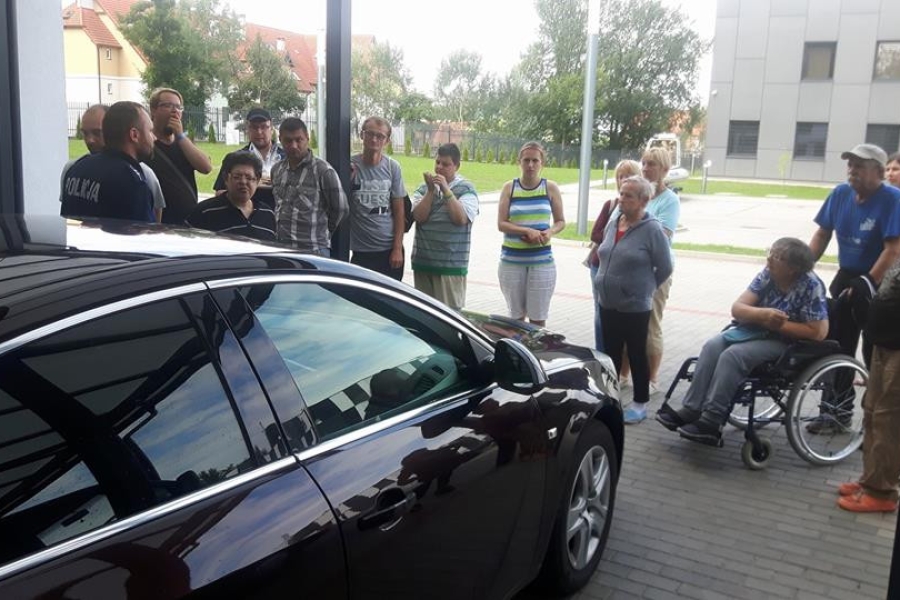 Grupa uczestników na tle służbowego samochodu