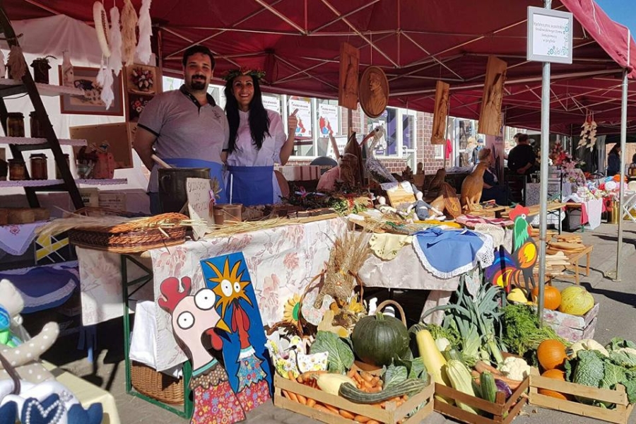 Uczestnik wraz z terapeutą pod namiotem prezentujący wykonane prace 