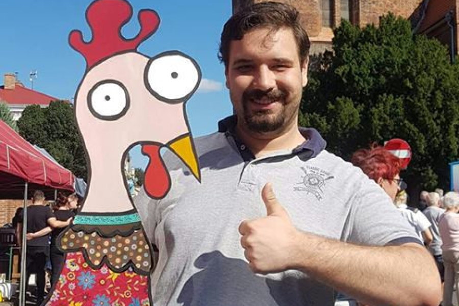 Uczestnik trzymający pracę przedstawiającą kurczaka na tle kościoła w Gryfinie