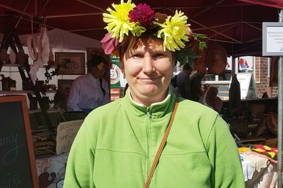 Uczestniczka z wiankiem na głowie, uśmiechająca się do zdjęcia