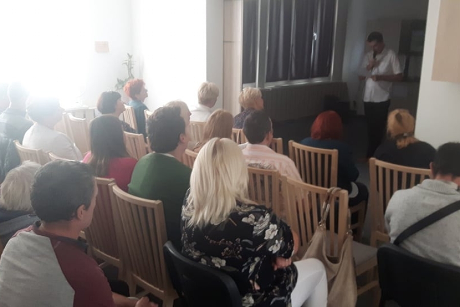 Uczestnicy wraz z gości siedzący na krzesłach słuchający wykładu