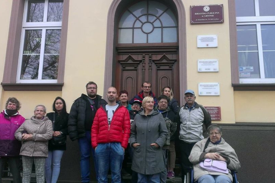 Zdjęcie uczestników oraz terapeutów przed wejściem do biblioteki