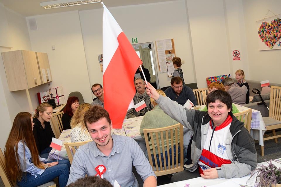 Uczestniczka trzymająca flagę polski na tle gości i uczestników
