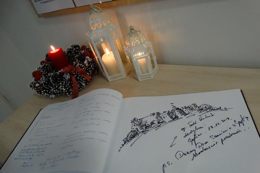 Zdjęcie wpisu z kroniki ŚDS na tle świeczki