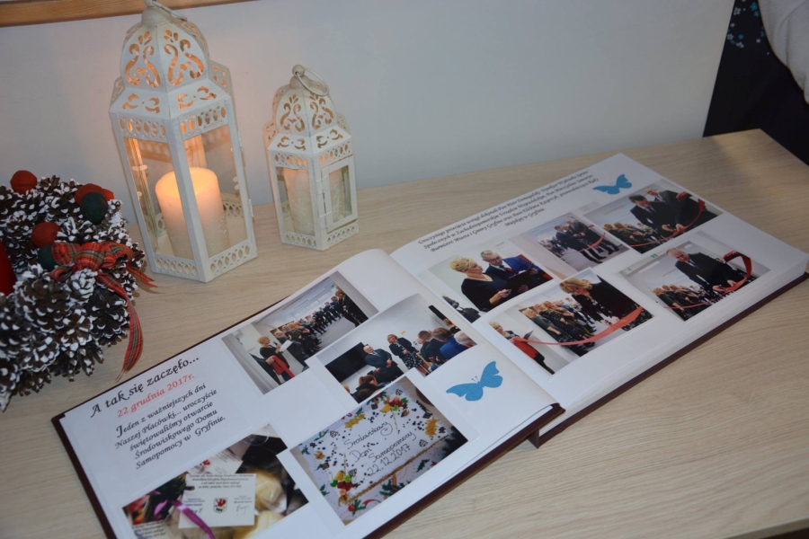 Zdjęcie wpisu z kroniki ze zdjęciami ŚDS na tle świeczki