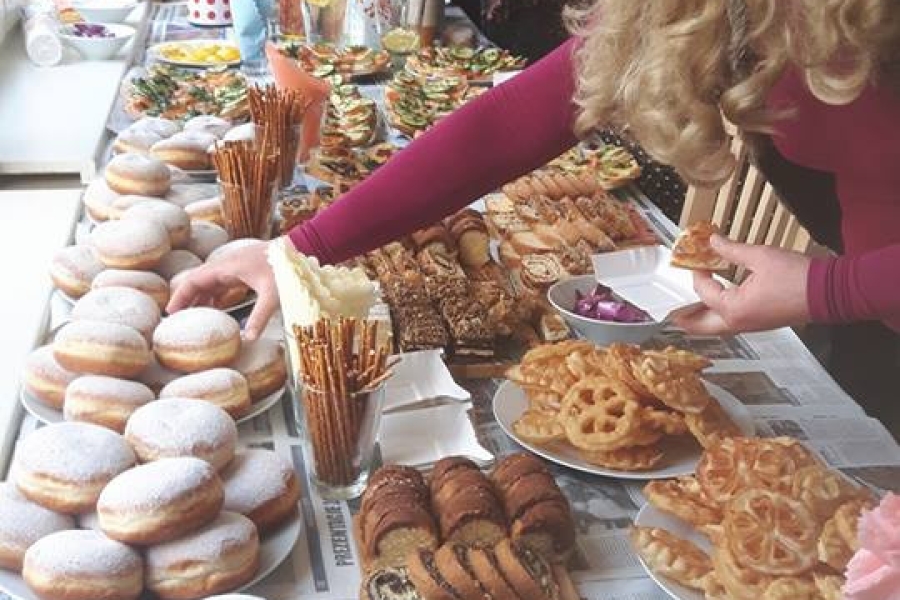 Grupa uczestników częstujących się wypiekami.
