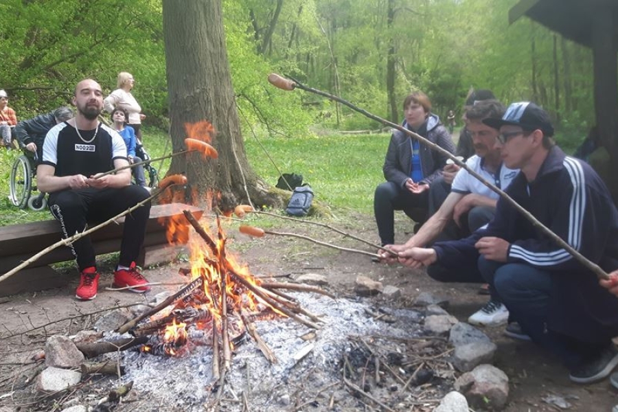 Grupa uczestników grilluje kiełbaski na kijach