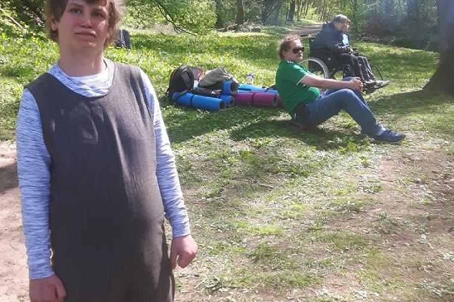 Troje uczestników wypoczywających na trawie wśród drzew