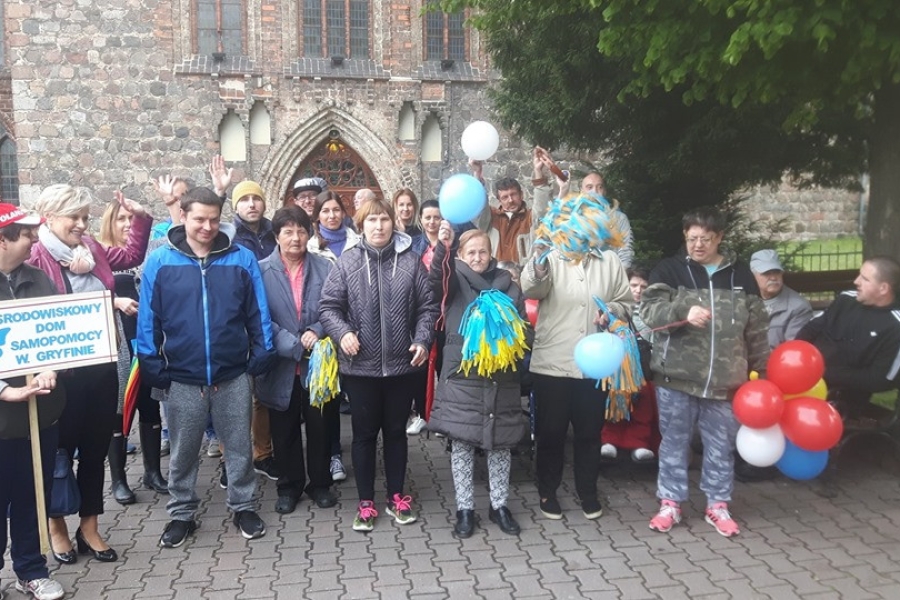 Grupa uczestników trzymająca balony na tle kościoła