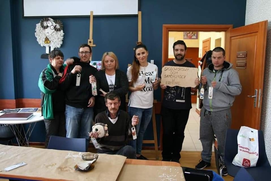 Uczestnicy wraz z terapeutami pozują do zdjęcie trzymając swoje rękodzieło.