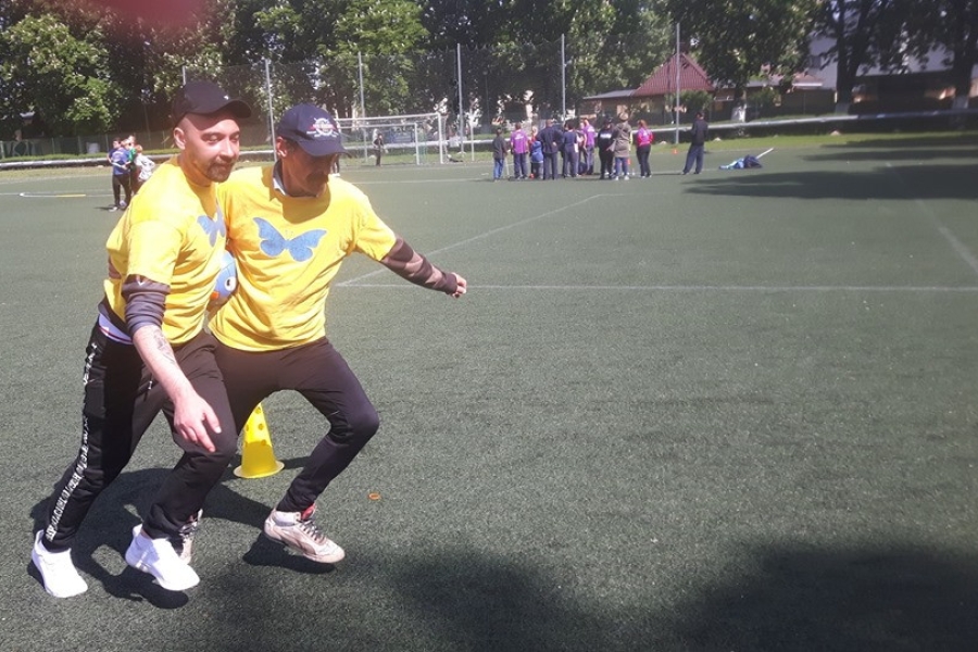 Dwoje uczestników biegnących razem z piłką między ich tułowiami