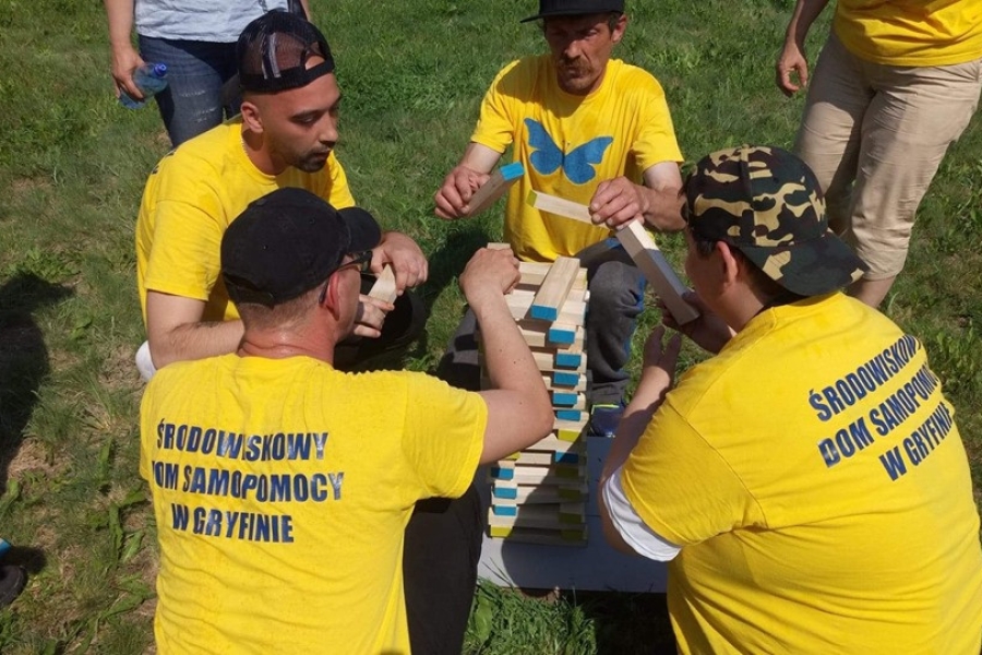 Uczestnicy ustawiający wieżę z drewnianych klocków.