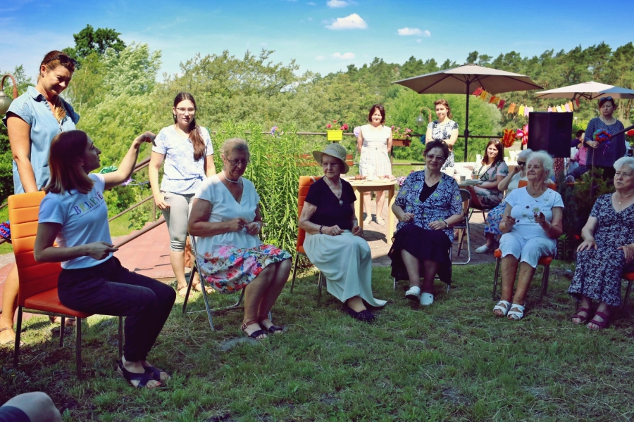 Grupa uczestniczek Domu Seniora podczas zabawy muzycznej w kręgu