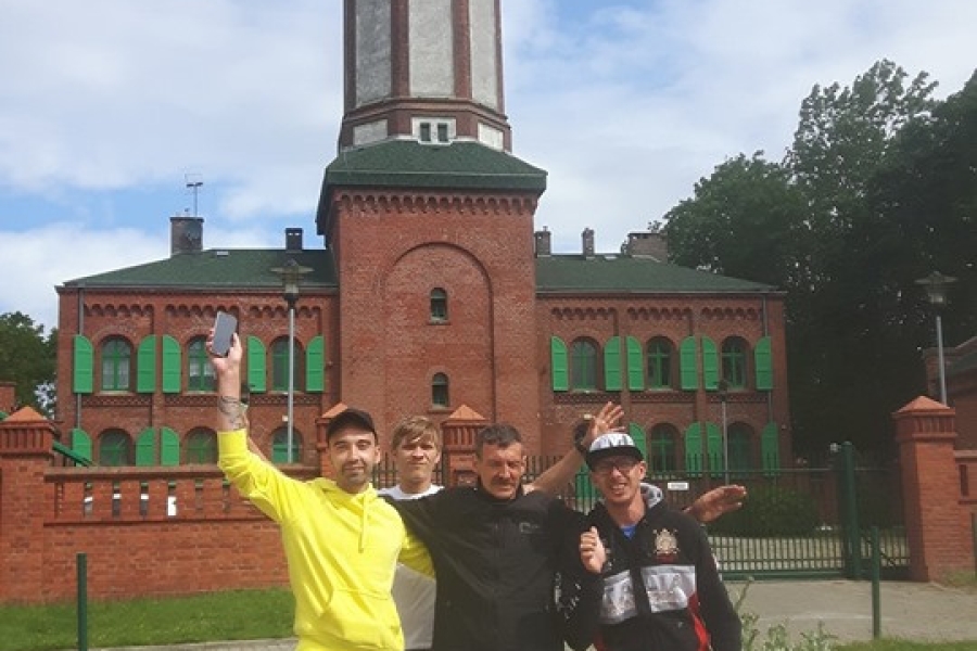 Czwórka uczestników na tle latarni morskiej w Niechorzu.