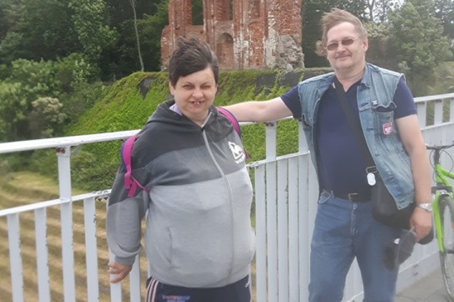 Dwójka uczestników stojących na molo na tle ruin kościoła w Trzęsaczu.