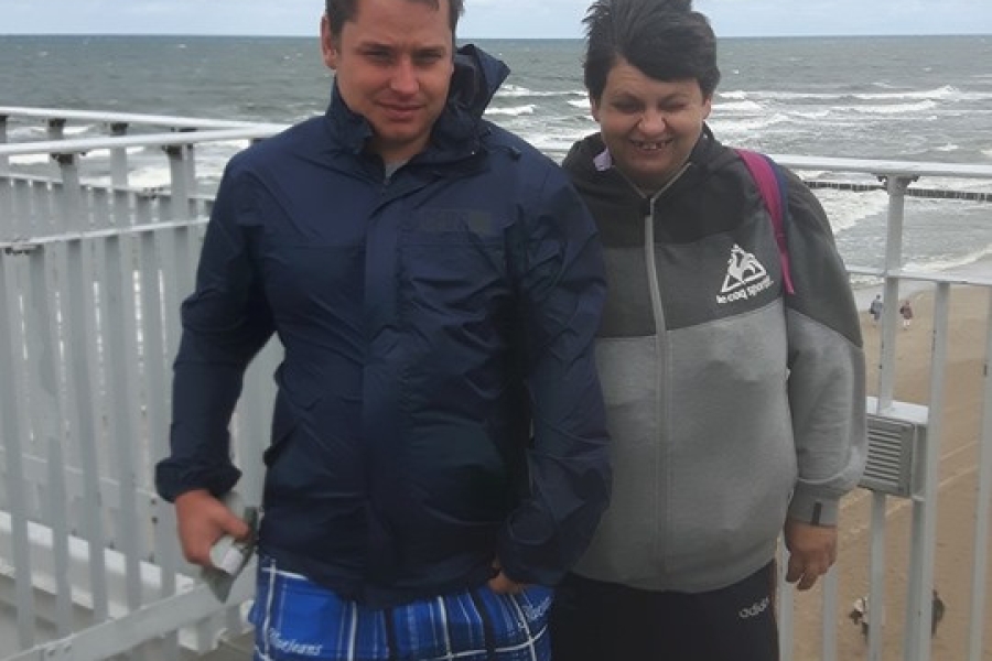 Dwójka uczestników pozująca na tle morza w wietrzną pogodę.