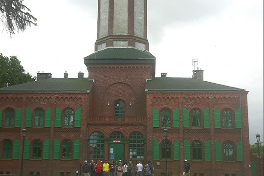 Grupa uczestników na tle latarni morskiej.