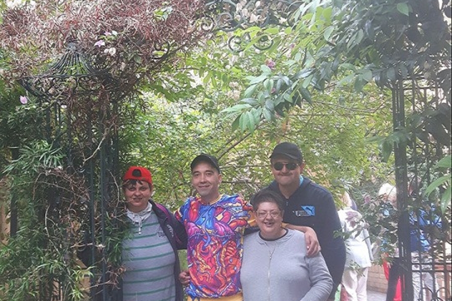 Grupa uczestników pozuje do zdjęcia pod kwiecistą bramą.