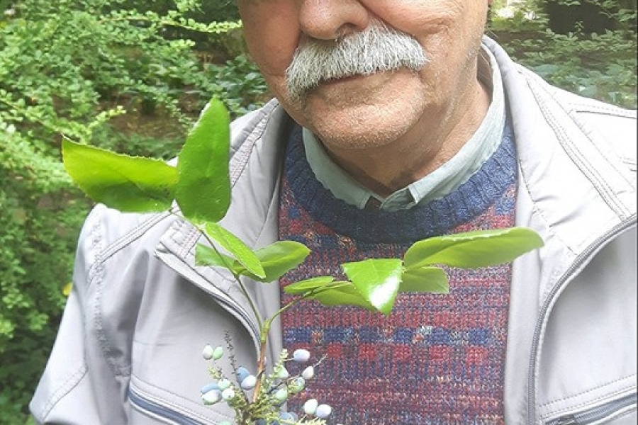 Uczestnik trzyma w dłoni gałązkę i pozuje do zdjęcia.