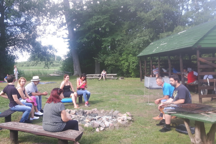 Uczestnicy wraz z terapeutami odpoczywają wokół miejsca na ognisko.