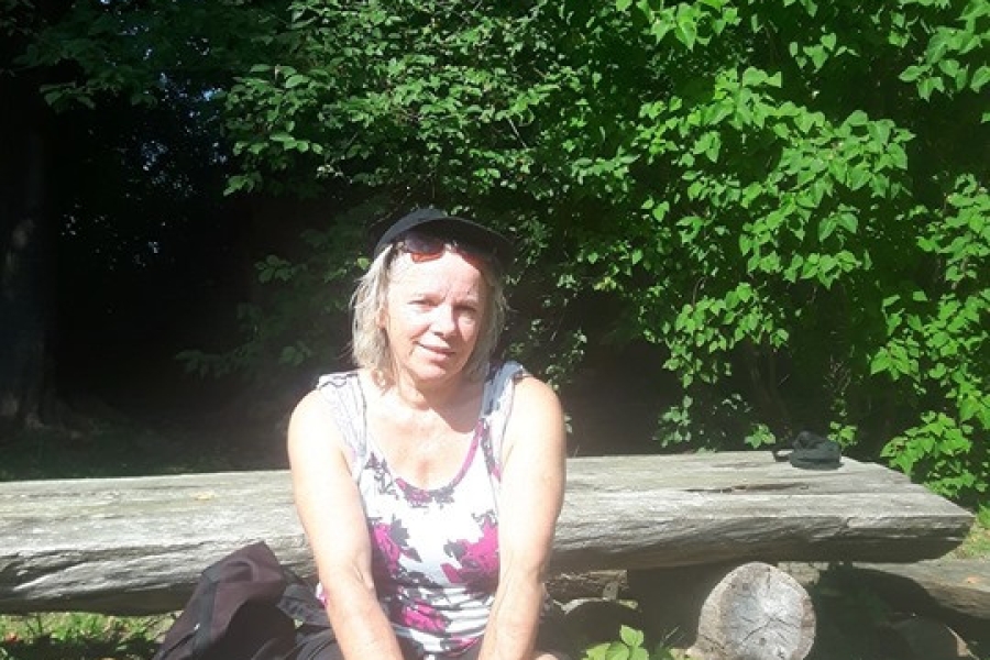 Uczestniczka siedzi na drewnianej ławce.