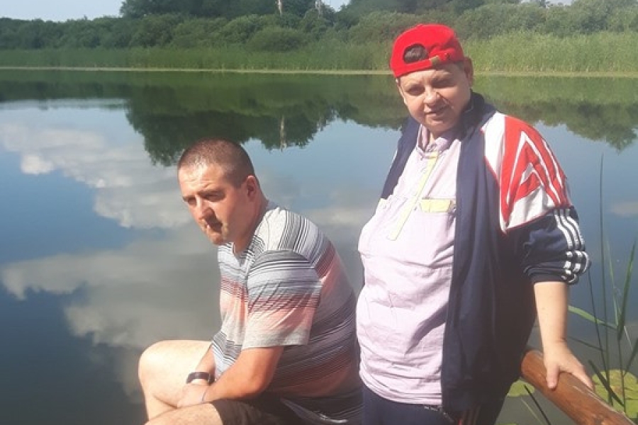 Dwoje uczestników odpoczywa na pomoście nad wodą.