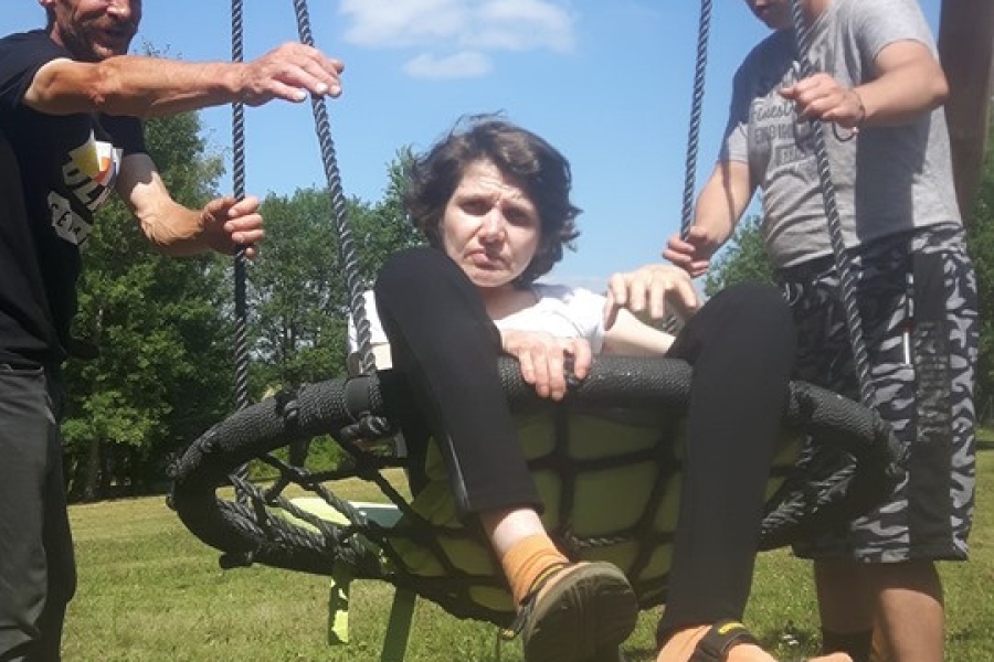 Dwoje uczestników huśta uczestniczkę. 