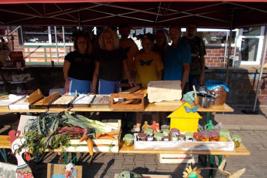  Uczestnicy wraz z terapeutami przy stoisku z rozmaitościami