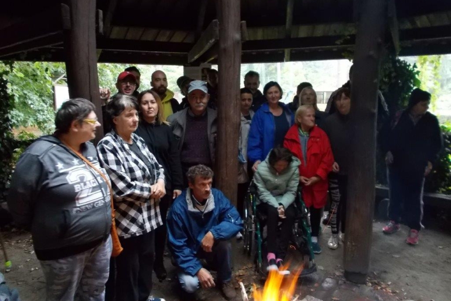 Uczestnicy stojący przy ognisku pod altaną
