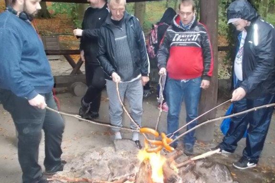 Uczestnicy pieczący kiełbaski nad ogniskiem