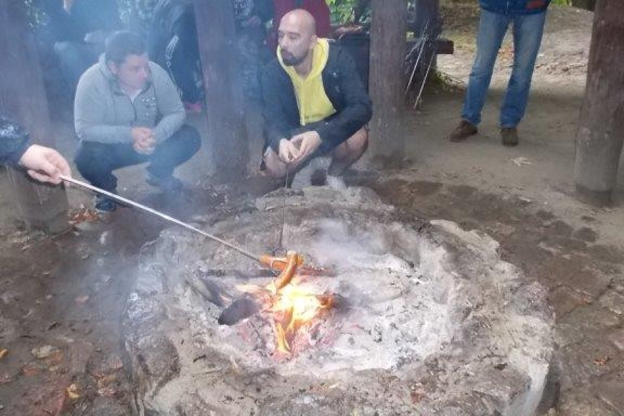 Uczestnik pieczący kiełbaski nad ogniskiem