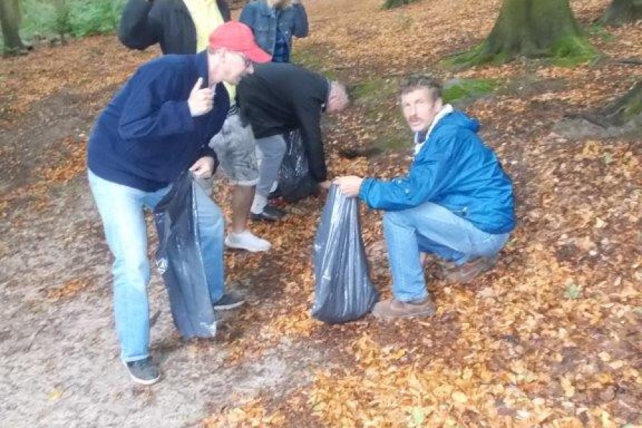 Uczestnicy pozujący do zdjęcia z workami na śmieci w lesie