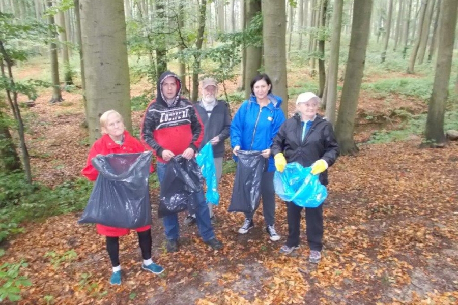 Uczestnicy pozujący do zdjęcia z workami na śmieci w lesie