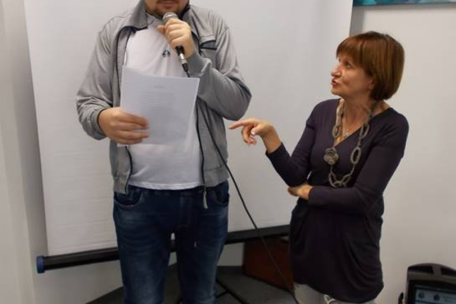 Uczestnik mówiący do mikrofonu stojący obok terapeutki