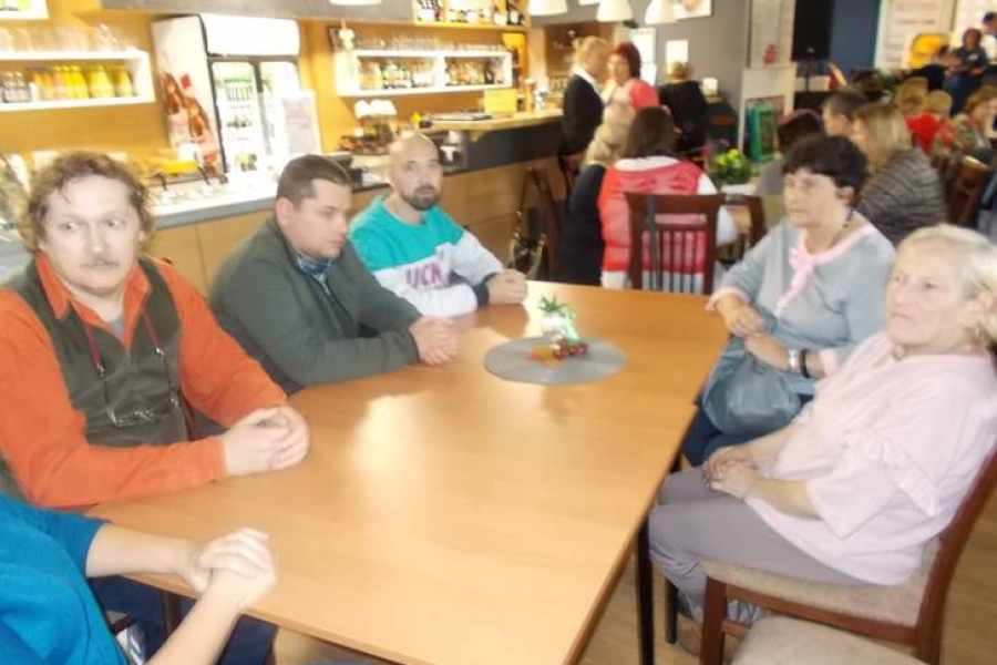 Grupa uczestników wraz z gośćmi siedzący przy stolikach