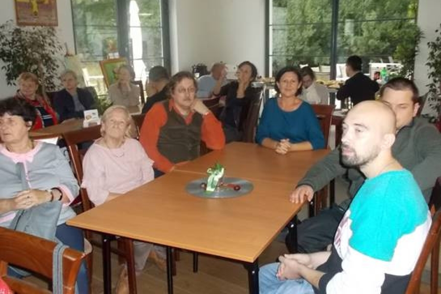 Grupa uczestników wraz z gośćmi siedzący przy stolikach