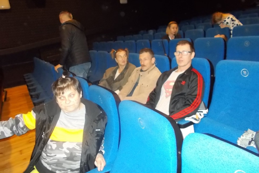 Uczestnicy siedzący na niebieskich krzesłach widowni