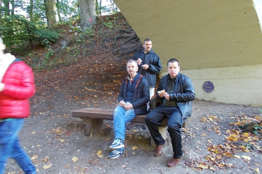 Uczestnicy jedzący na ławce pod kładką