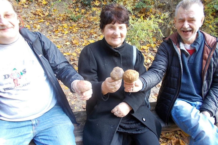 Troje uśmiechniętych uczestników trzymająca grzyby