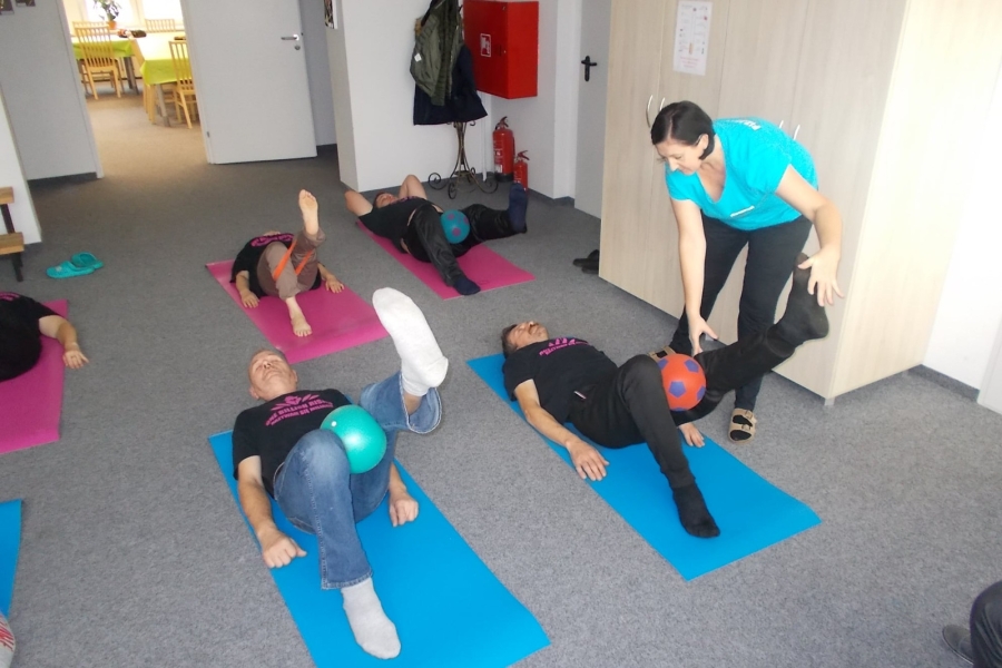 Uczestnicy leżący na karimatach unoszący nogę do góry