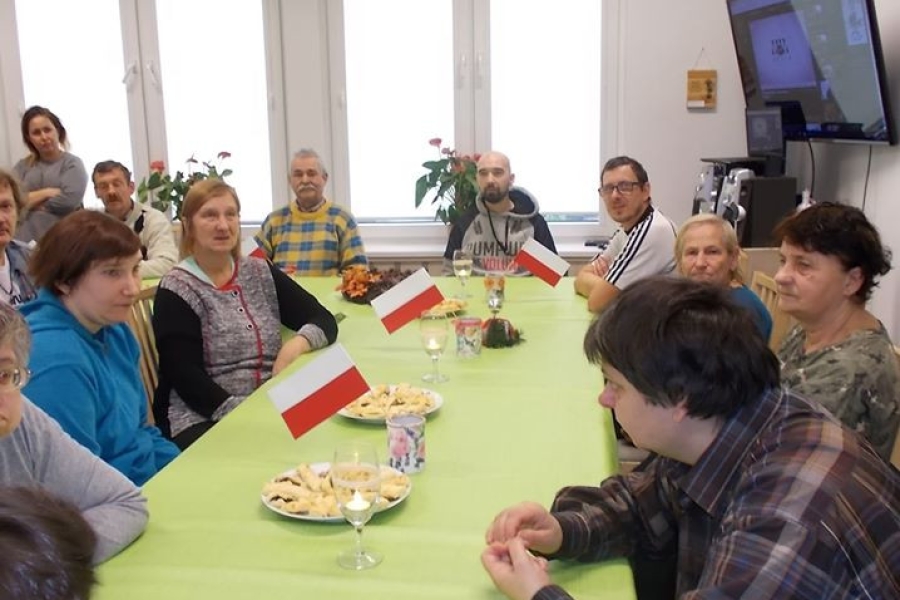 Uczestnicy przy stole przyozdobionym flagami Polski