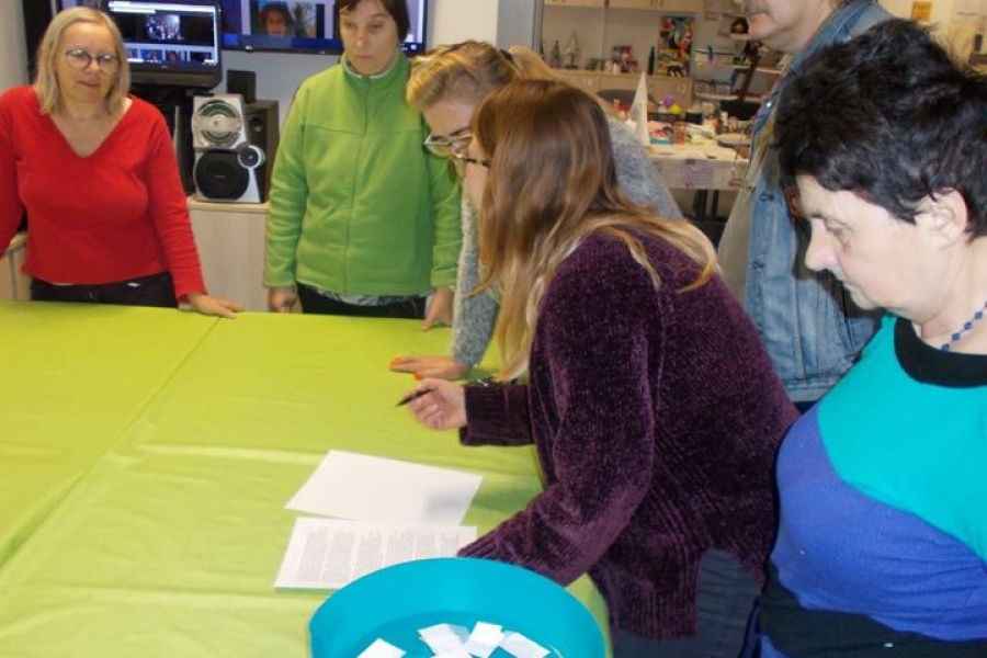 Uczestnicy przy stole z wróżbami czytający zasady