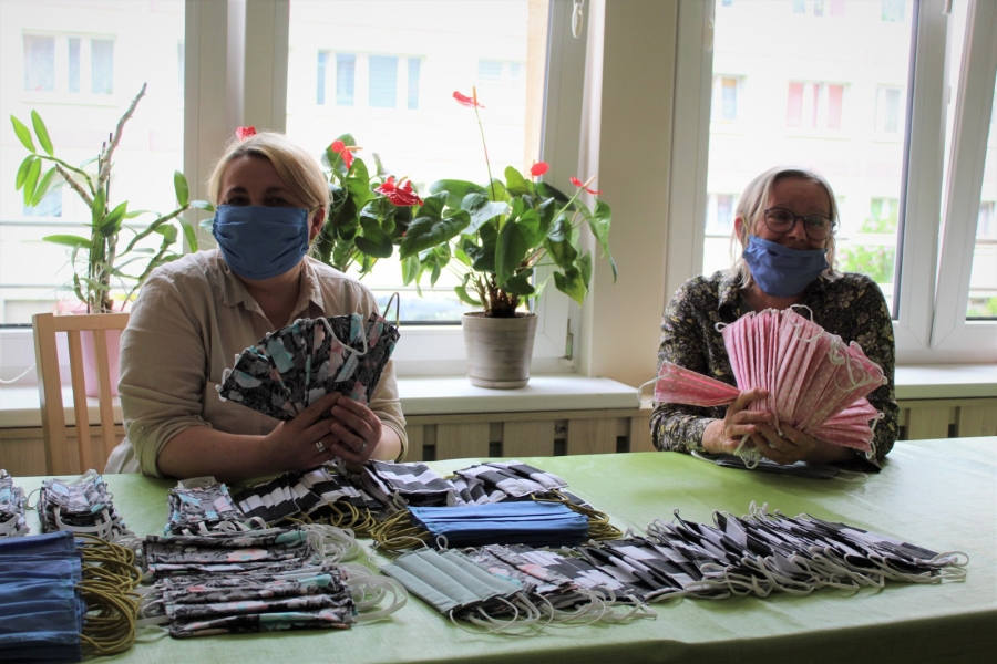 Opiekun medyczny wraz z uczestniczką prezentująca uszyte maseczki