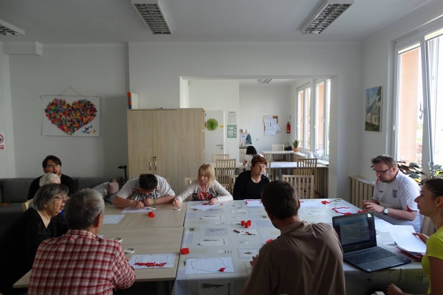 Uczestnicy ŚDS siedzący przy wspólnym, wielkim stole w trakcie prac z rękodzieła