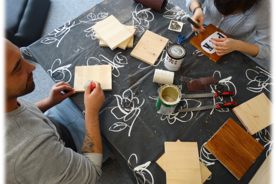 Grupa uczestników wykonująca prace rękodzielnicze z drewna w ramach pracowni rzemiosł różnych 