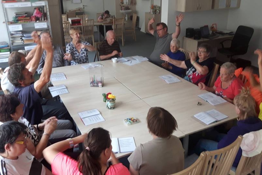 Uczestnicy w trakcie wspólnego śpiewania unoszą ręce w górze