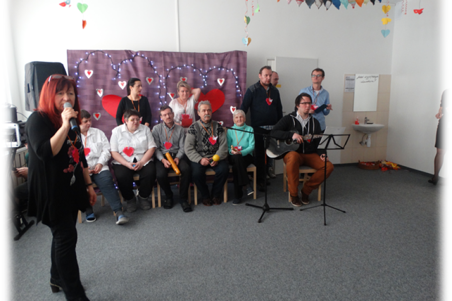 Wokalistka razem z  siedzącymi uczestnikami ŚDS wykonuje utwór muzyczny